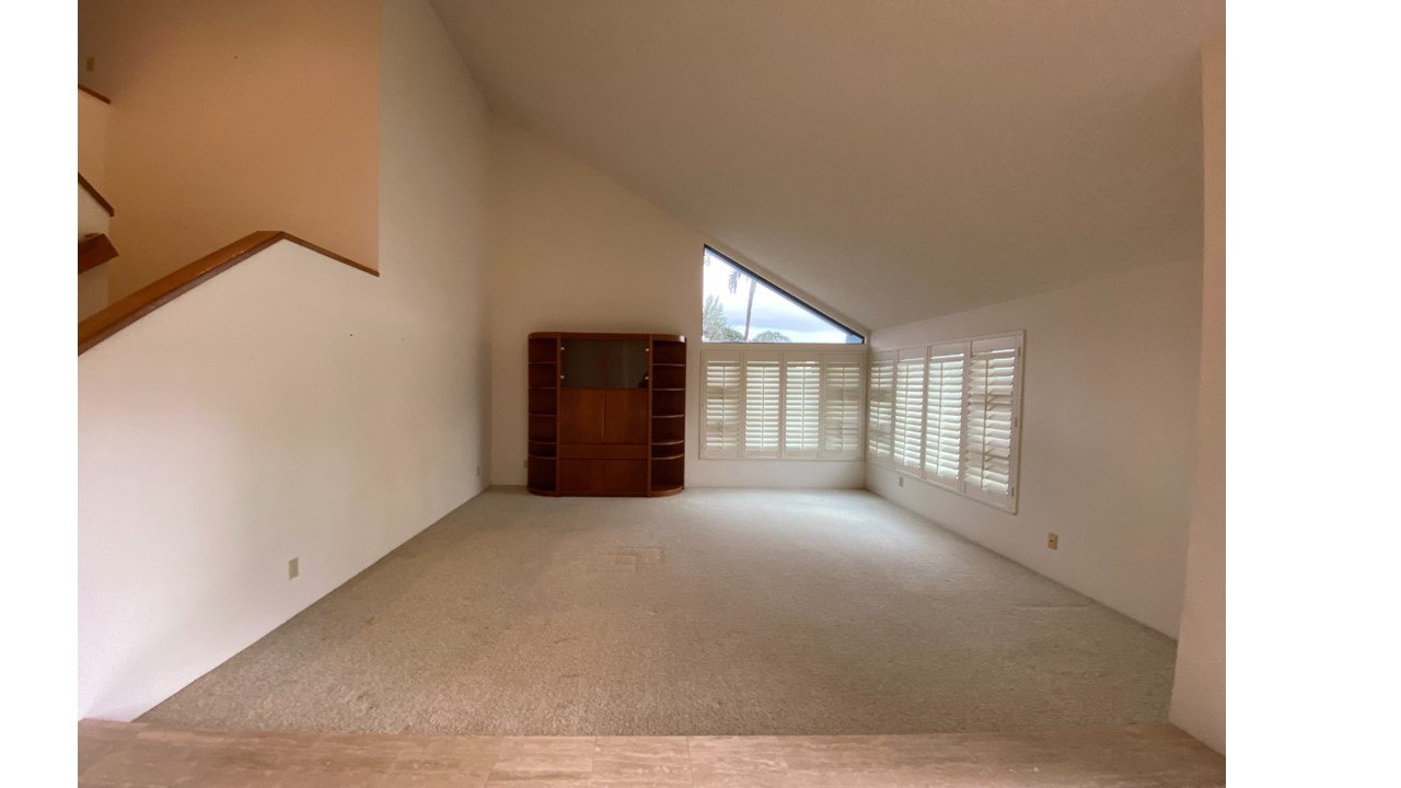 A room with a wooden cabinet and a window with blinds.